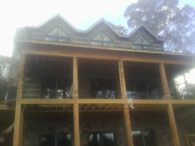 Dormers and porch framing on a large log home under construction — Roof Coating work by our crew in Clarksdale